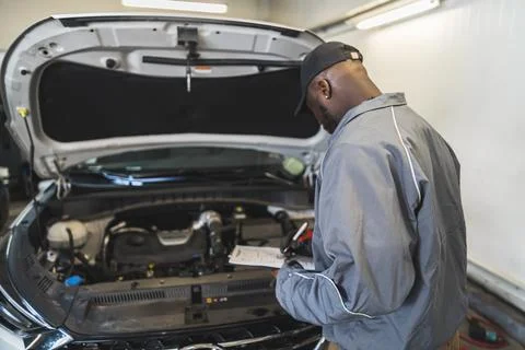 Mechanic checking car engine under the open hood at a service shop Fotos de archivo