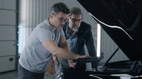 Mechanic checking car engine using tablet Stock Photos