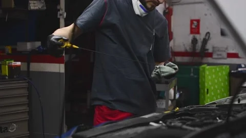 Mechanic checking the car oil level looking at the engine dipstick Stock Footage 132304019