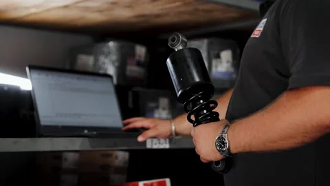 Mechanic checking car part information, holding a shock absorber for vehicle Stock Footage 333705862