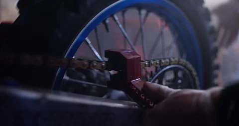 Mechanic checking chain of motorcycle tyre with spanner in shop Stock Footage 116360827