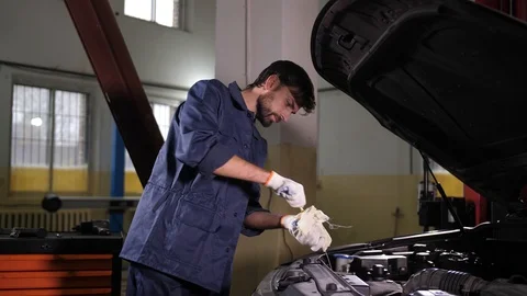 Mechanic checking engine oil level in car workshop Stock Footage 123504812