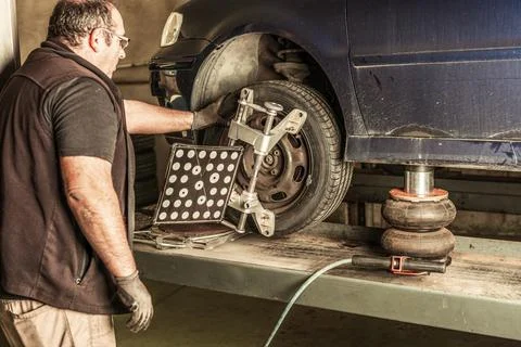 Mechanic checking the operation of a pneumatic jack under a car to lift it Stock Photos