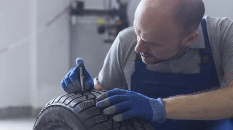 Mechanic checking tire tread depth and wear Stock Photos