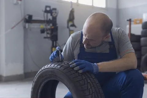 Mechanic checking tire tread depth and wear Stock Photos