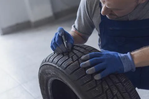 Mechanic checking tire tread depth and wear Stock Photos