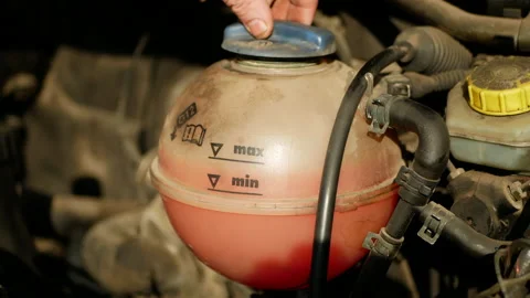 Mechanic checks the expansion tank with pink antifreeze. Vehicle coolant level Stock Footage 165093653