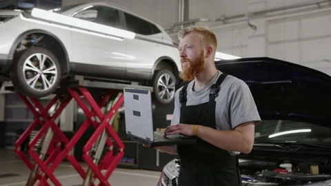 Mechanic in a clean uniform with the help of a professionally diagnostic laptop Stock Footage 212064274