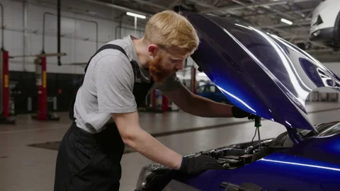 Mechanic in a clean uniform while repairing a car in a modern service station Stock Footage 212058934