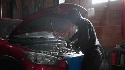 Mechanic cleaning a car engine bay with a compressed air gun in a garage Stock Footage 315006852
