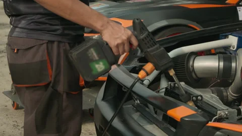 Mechanic cleaning a car engine bay using a high-pressure air blower. Stock Footage 323717987