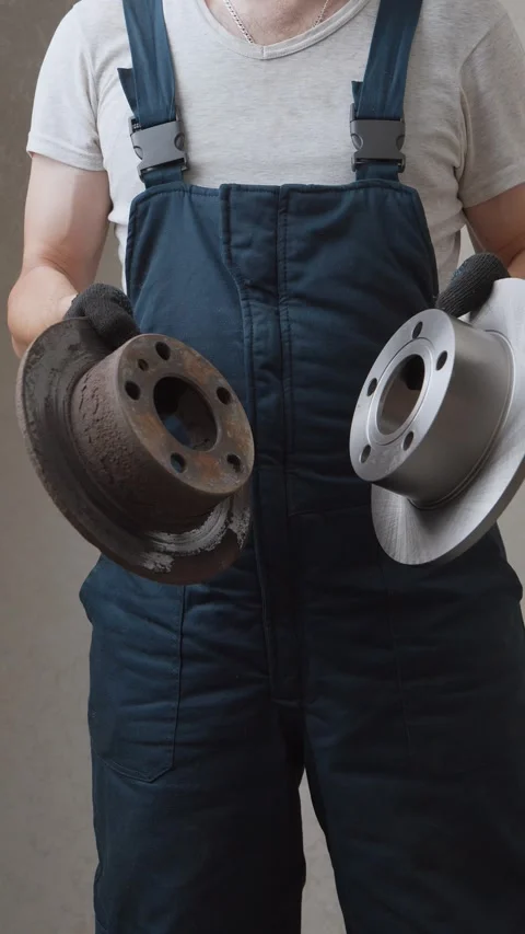 Mechanic comparing old rusted brake disc with new one Stock Footage 326150336