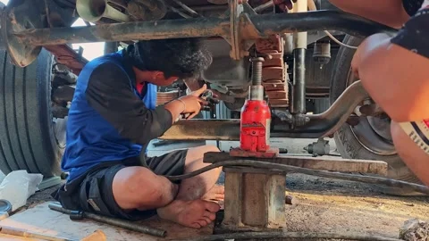 Mechanic conducting maintenance on a truck using tools and equipment beneath Stock Footage 341000528