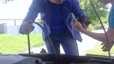 A mechanic dad teaches his son how to change the timing belt and car cooling pum Stock Footage 243077533