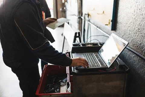 Mechanic diagnosing the car with the computer. Concept of car repair. Stock Photos