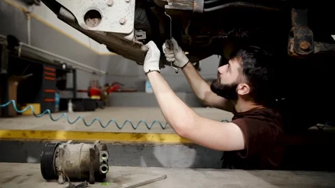Mechanic diagnosing car undercarriage, performing vehicle inspection and repair Stock Footage 333705846