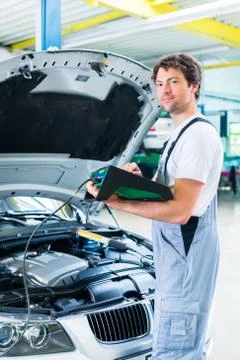 Mechanic with diagnostic tool in car workshop Stock Photos