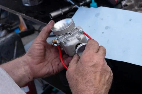 A mechanic disassembles a carburetor Stock Photos