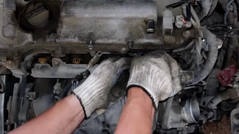 A mechanic disassembles engine parts beneath a metal valve cover. Stock Footage 339491874