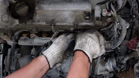 A mechanic disassembles engine parts beneath a metal valve cover. Stock Footage 339492011