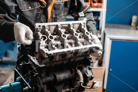 Mechanic disassembling the engine, overhaul.. Engine on a repair stand with Stock Photos