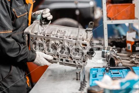 Mechanic disassembling the engine, overhaul.. Engine on a repair stand with Stock Photos