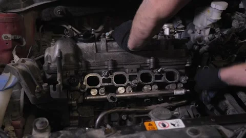 A mechanic disassembling the engine under the hood of a car at a service station Stock Footage 339787947