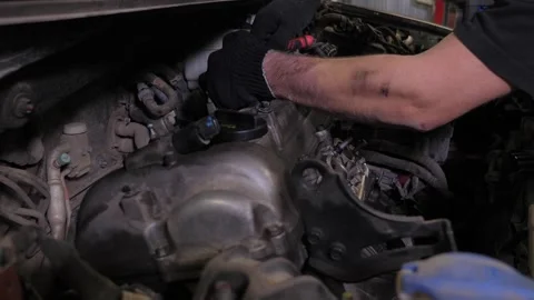 A mechanic disassembling the engine under the hood of a car at a service station Stock Footage 340245717