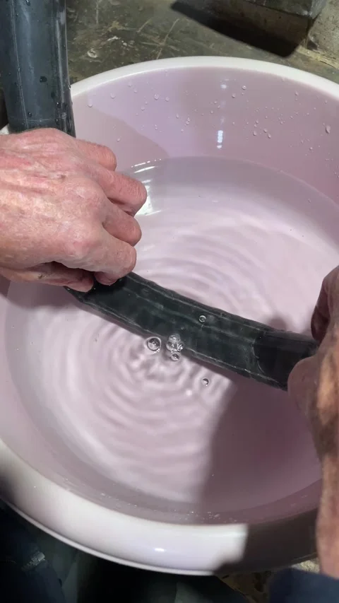 Mechanic discovered puncture using basin of water in inner tube of bicycle Stock Footage 334047831