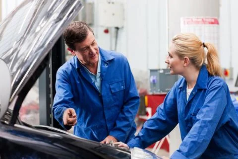 Mechanic discussing car engine with apprentice Stock Photos