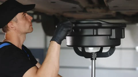 Mechanic drain the old oil from the engine through the drain plug. Changing the Stock Footage 203877752