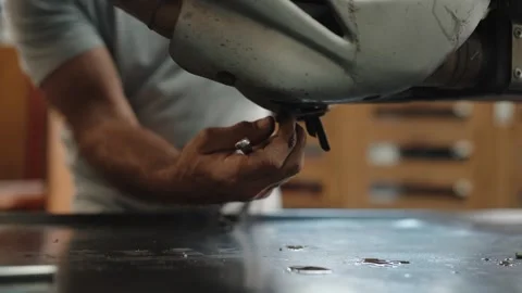 Mechanic draining oil under a motorcycle in a workshop Stock Footage 346184573
