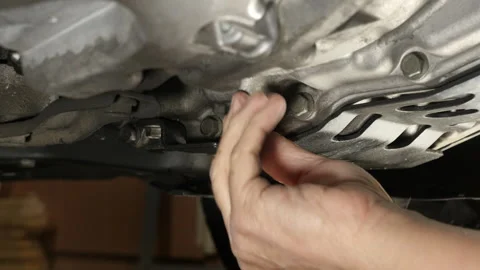 A mechanic draining transmission fluid while servicing a car Stock Footage 221277790