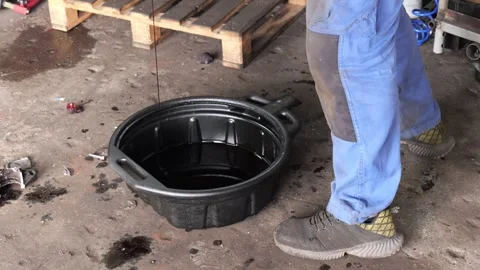 Mechanic draining used engine oil change at garage service station Vidéo 346411019