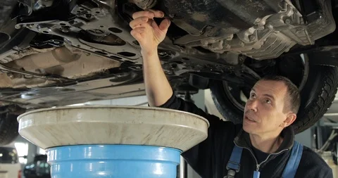 Mechanic Drains Old Used Engine Oil From A Car Stock-Footage 124958802