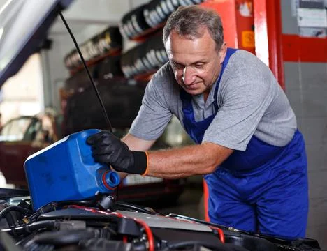 Mechanic engaged in replacement of engine oil Stock Photos