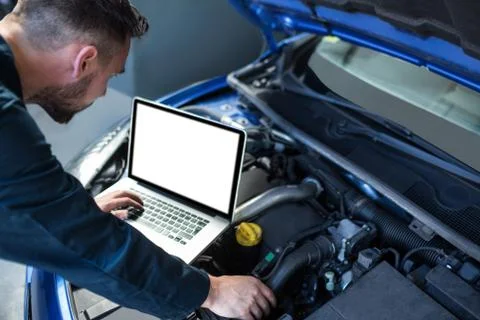 Mechanic examining car engine with help of laptop 스톡 사진