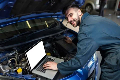 Mechanic examining car engine with help of laptop 스톡 사진