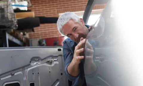 Mechanic examining car panel in auto repair shop Stock Photos