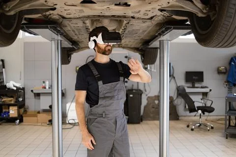 Mechanic examining car using virtual glasses in modern workshop Stock Photos
