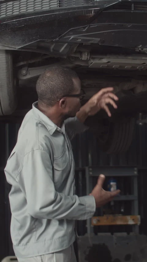 Mechanic Explaining Reason of Oil Leaking under Car Bottom Stock Footage 259609737