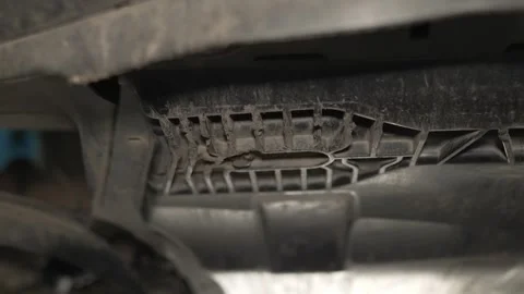 A mechanic fits a textured plastic skid plate under car. Stock Footage 341333698