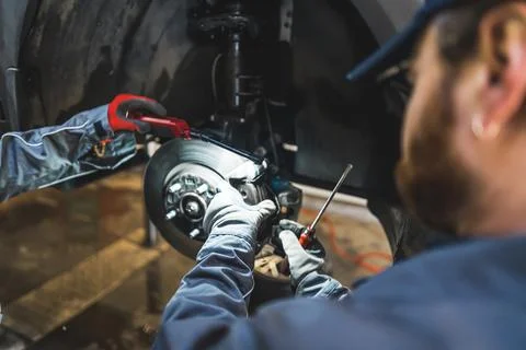 Mechanic fixing car tyres using a screw driver and tools in an auto repair shop Foto stock