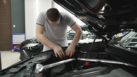 Mechanic fixing components under car hood Stock Footage 305872157