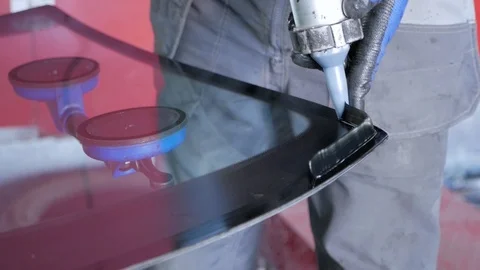 A mechanic is fixing the front window on the car. 库存影片 121280587