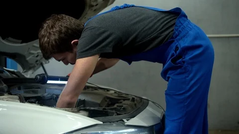Mechanic with flashlight examines the motor of car Video stock 124258531