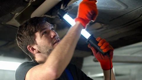 Mechanic with flashlight repairs a car, close up Stock Footage 124259203