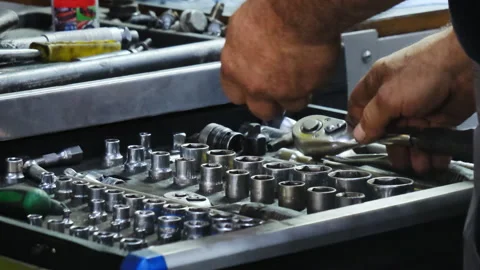 Mechanic in grey jumpsuit arranges wrenches in drawers of cabinet Video stock 324709786
