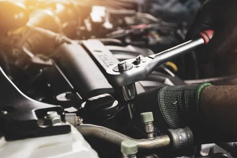 The Mechanic hand is fasten the bolt with the socket wrench Stock Photos