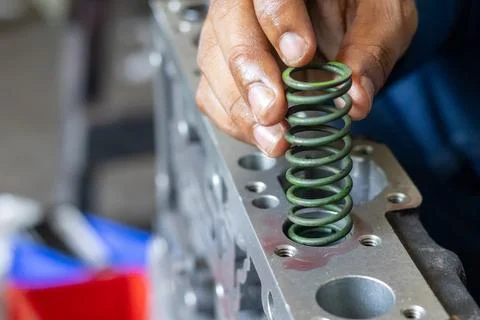 Mechanic Hand Inserting Coil Spring Into Hydraulic Valve Body Unit. Stock Photos